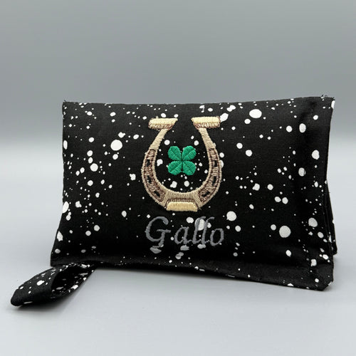 Black and White Speckled horse bit warmer with horseshoe, clover, and Gallo personalization on grey background