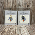 Two packages of Ever So Clever Creations carrot charms on a wood background