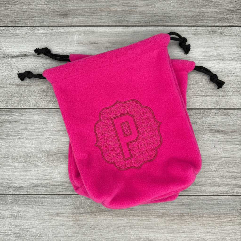 Pair of hot pink stirrup covers with embossed 'P' monogram on wood background. 