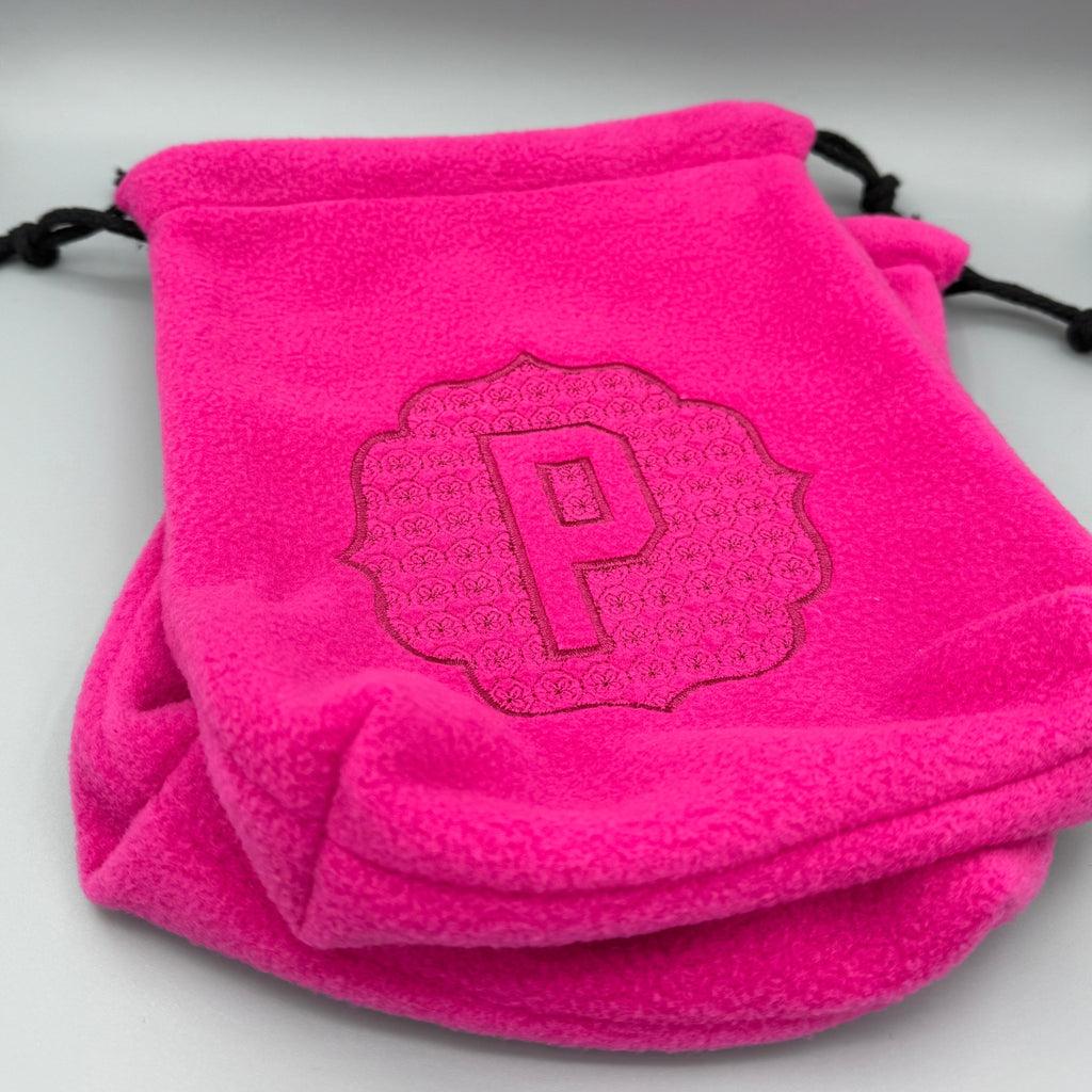 Close up of Hot Pink stirrup covers with embossed 'P' monogram on gray background. 