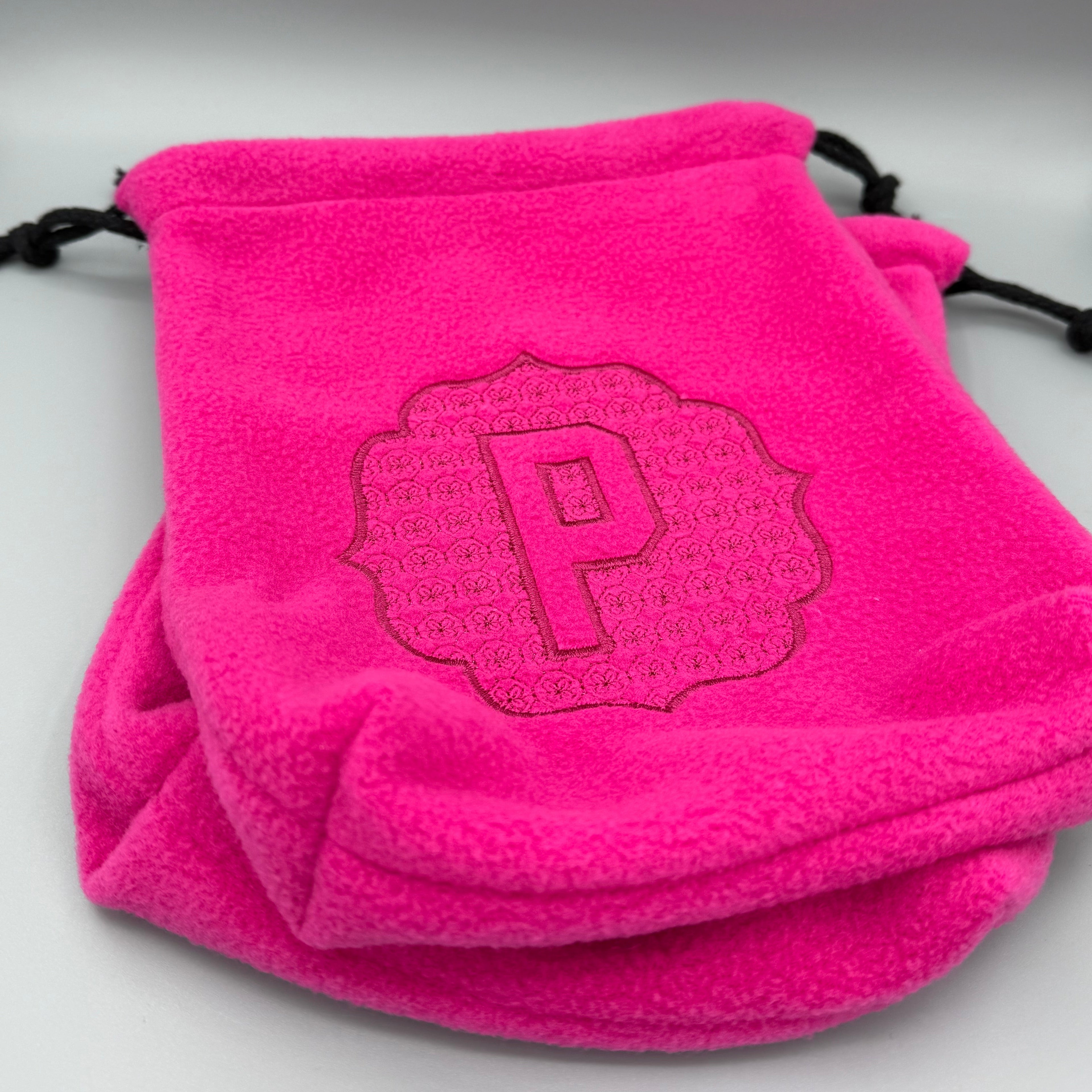 Close up of Hot Pink stirrup covers with embossed 'P' monogram on gray background. 