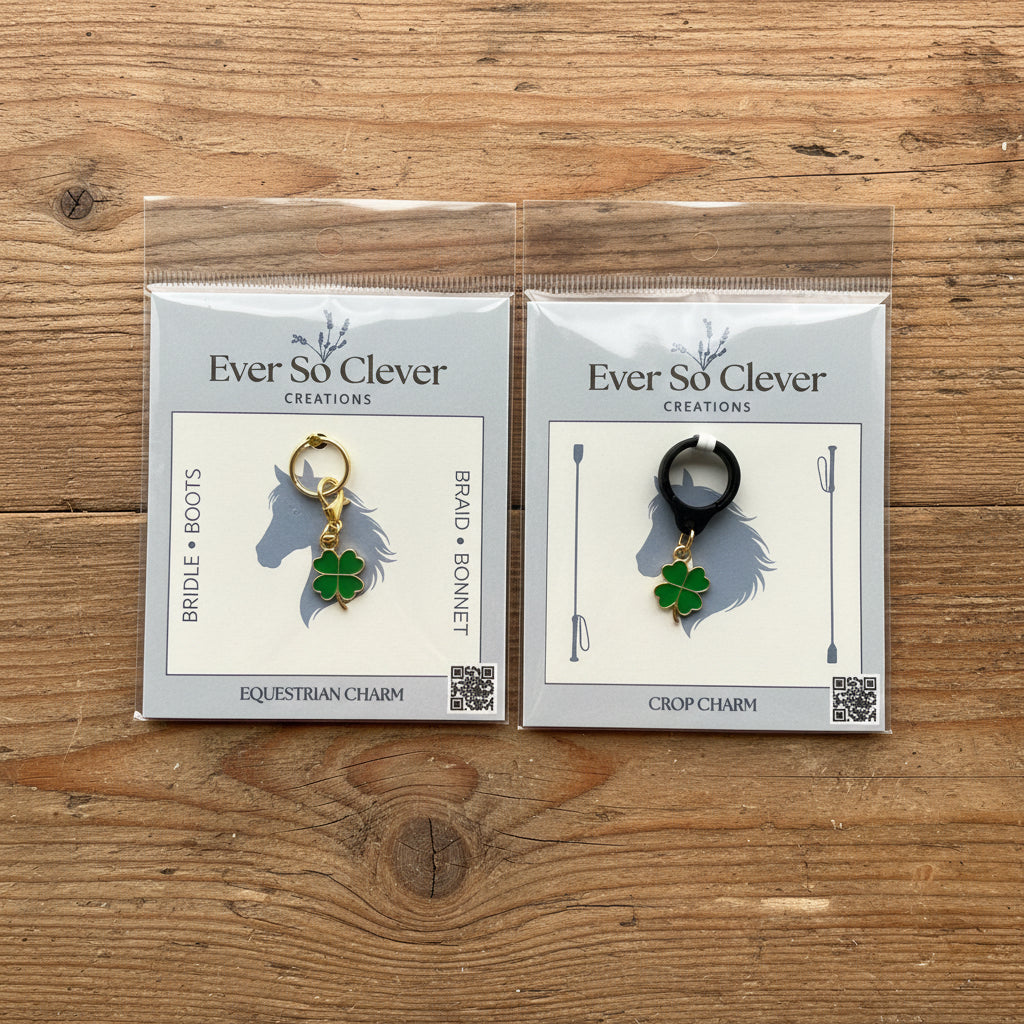 Two packages of Ever So Clever Creations four-leaf clover charms on a wood background