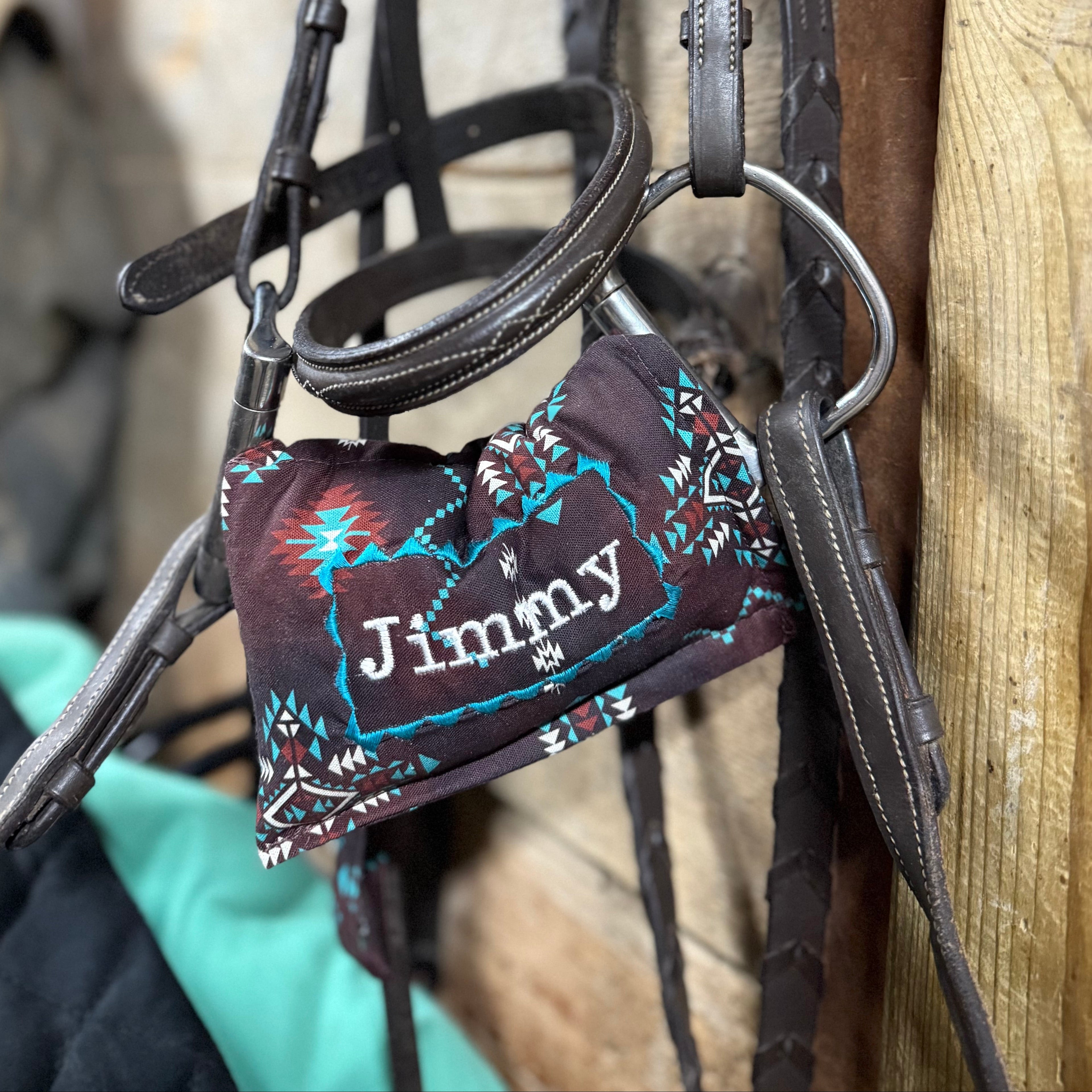 Horse bridle with a personalized bit warmer on a wooden background