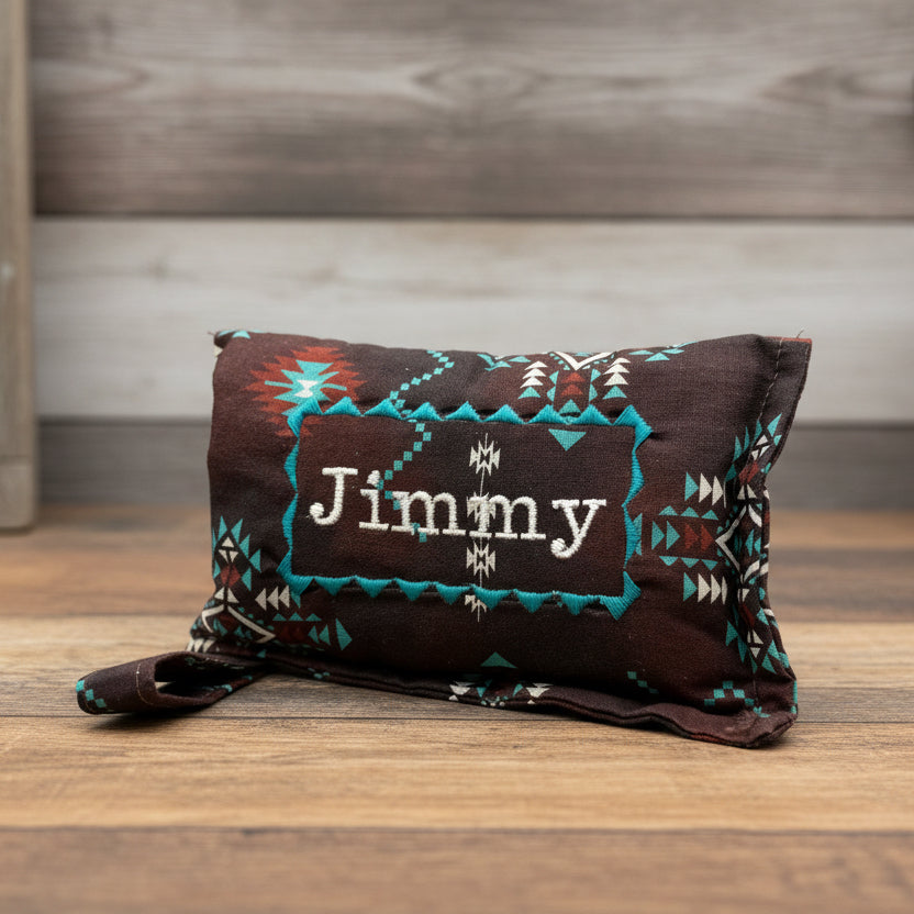 Brown bit warmer with tribal patterns and 'Jimmy' personalization on wooden background