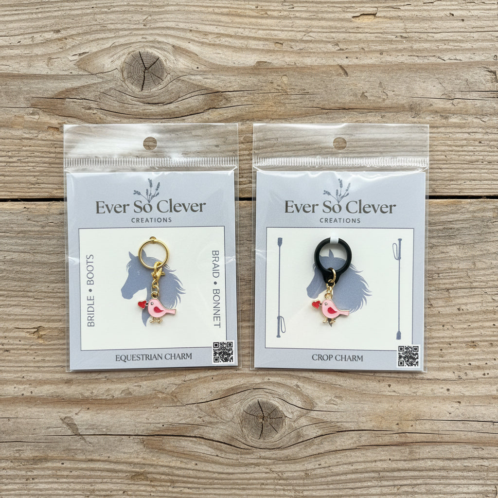 Two love bird charms in Ever So Clever packaging on wood background. 