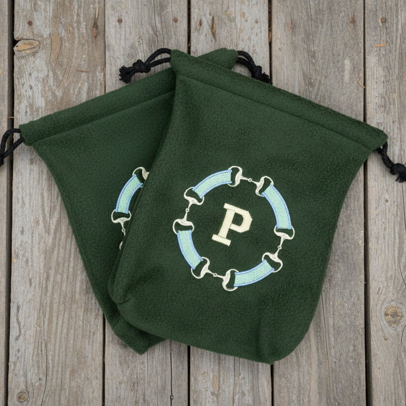 Green snaffle bit monogram stirrup covers with a 'P' on a wooden background.